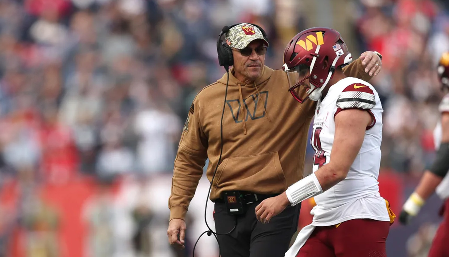 Washington Commanders quarterback Sam Howell and head coach Ron Rivera talking on the sidelines